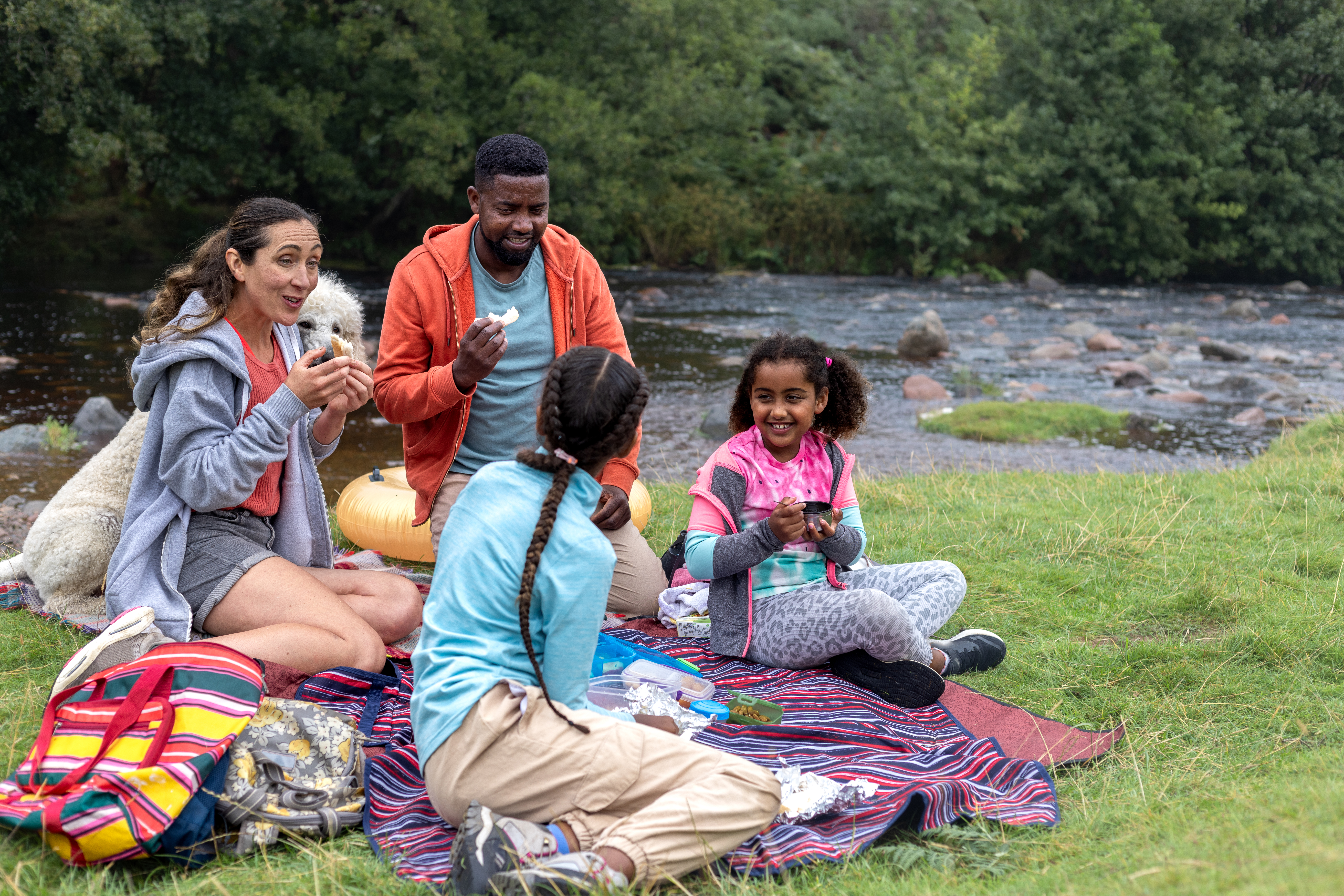 Family enjoying school holidays with a picnic in the park by a lake